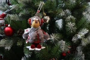 Detail of cute reindeer plush ornament hanging on a Christmas tree with festive decorations