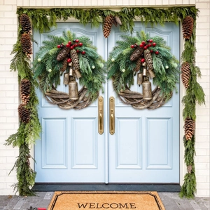 Christmas pine cone wreath set with vintage gold bells and red berries on blue double doors
