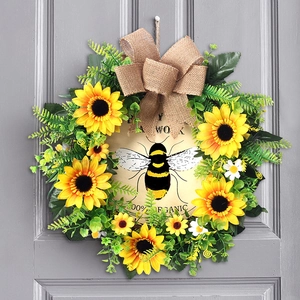 Detail of sunflower bee wreath with burlap bow and organic sign on grey wooden door