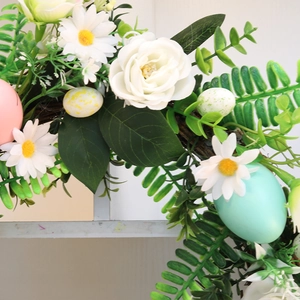 Easter wreath with white roses, daisies, colorful eggs and green leaves for door decor