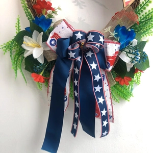 Patriotic USA Independence Day wreath with red white blue flowers and star bow on rattan