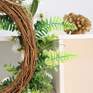 Close-up of Easter wreath with white foam eggs, daisies and green fern on natural rattan base