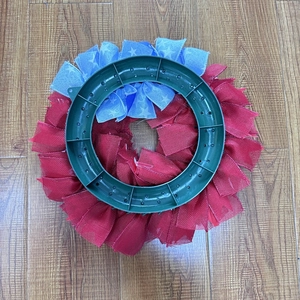 Patriotic July 4th door wreath with red, white, and blue ribbons on a round green frame