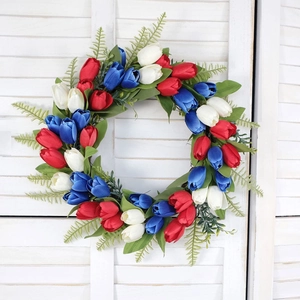 Detail of red white and blue tulip wreath hanging on white wooden shutter door