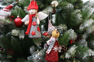 Detail showing knit Christmas angel and reindeer dolls hanging on a festive pine tree