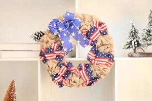 Close-up of patriotic burlap wreath with American flag bows on white shelf
