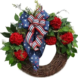 Patriotic Independence Day wreath with red flowers and US flag bow on rattan base
