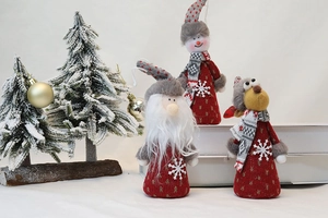 Three plush Christmas ornaments with red knitted hats and scarves in a snowy setting