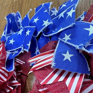 Patriotic 4th of July wreath decoration made of red, white, and blue burlap fabric