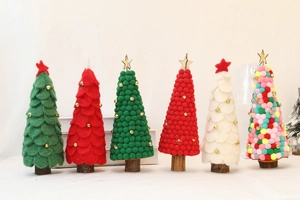 Mini wool felt Christmas trees with wooden bases and colorful pom poms on white background