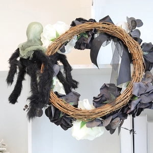 Halloween wreath with black roses, a large furry spider, and ribbons on a rattan base