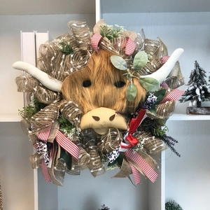 Close-up of highland cow wreath with burlap ribbons, greenery and artificial fur texture