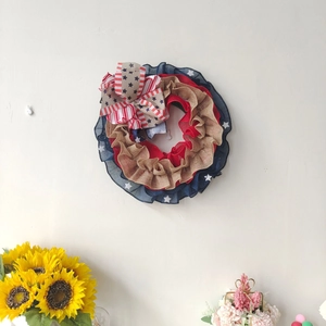 Detailed macro view of the burlap wreath with star and stripe pattern bow on white wall