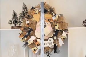 Close-up of a rustic burlap dog wreath with bone-shaped sign and decorative ribbons