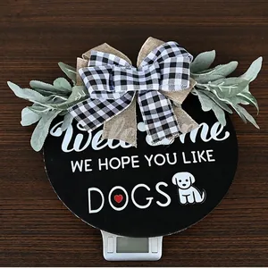 Round wooden Welcome sign with dog theme, buffalo plaid bow, and green artificial leaves