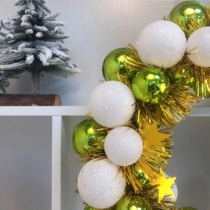 Christmas wreath with green shiny balls, white glitter baubles and golden tinsel stars