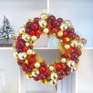 Close-up of a festive Christmas wreath with red and gold baubles and stars on a white shelf