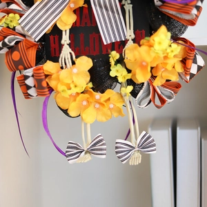 Halloween wreath with orange flowers, skull accents, and Happy Halloween sign