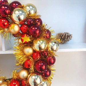Macro detail of red and gold Christmas ball wreath with glitter stars and pinecone decor