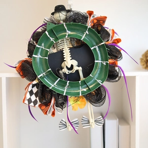 Halloween skull wreath with orange black ribbons and purple feathers on plastic frame