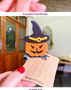 Macro shot of a 3D pumpkin wizard hat hair clip with glitter details on a kraft paper card