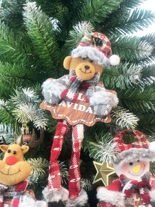 Detailed view of Christmas plush ornaments with Feliz Navidad wooden sign on a pine branch