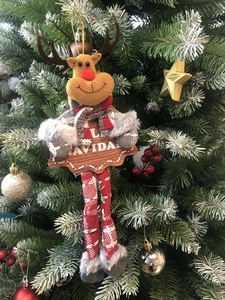 Close-up of reindeer hanging ornament with Feliz Navidad sign on a Christmas tree