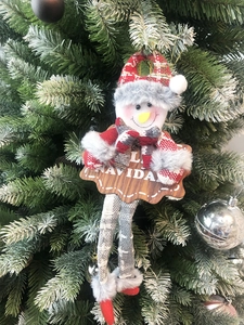 Detail of Christmas snowman ornament with wooden Navidad sign hanging on a holiday tree