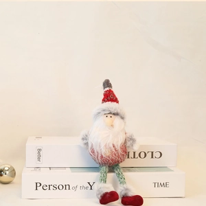 Knitted Santa Claus doll with red striped hat and curly beard on white decorative books