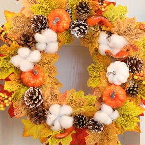 Couronne d'automne avec feuilles d'érable citrouilles et coton sur un mur blanc