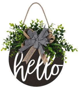 Close-up of wooden door wreath with white hello script, greenery and plaid bow decor