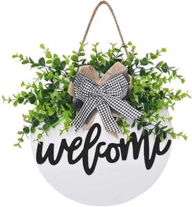 Close-up of the welcome door sign with faux greenery and burlap bow detail