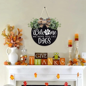 Black round wooden welcome door sign with eucalyptus leaves and dog paw print pattern