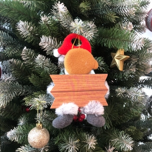 Close-up of a Christmas tree plush ornament featuring a DIY wooden blank plaque detail