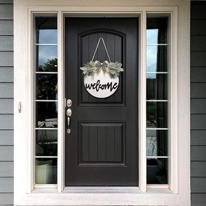 White wooden welcome wreath sign with green leaves and plaid bow on a black front door