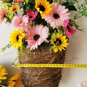 Detail view of woven rattan wall basket with artificial gerbera flowers and measuring tape
