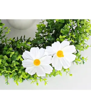 Artificial eucalyptus wreath with white daisies and green leaves on gray background