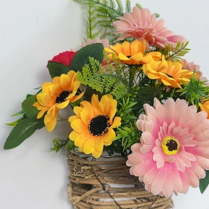Detailed close-up of vibrant artificial Gerbera flowers in a rustic rattan basket hanger