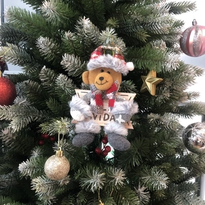 Detail view of a plush Christmas bear ornament with a Navidad star sign on a decorated tree