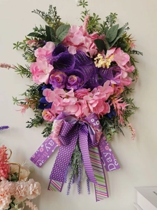 Detail of floral wreath with pink hydrangeas, purple roses and dotted ribbon bow