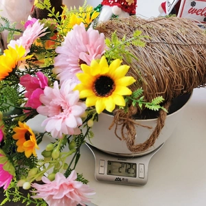 Artificial flower wreath with sunflowers and daisies in a rustic woven wicker basket