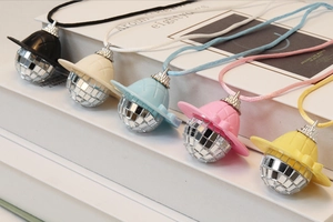 Detail view of mini disco ball hat pendants in five colors on a decorative book