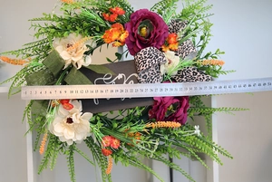 Detail of autumn wreath with roses and wood sign showing size with a metal ruler