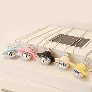 Detailed view of colorful mini cowboy hat disco ball pendant necklaces on books