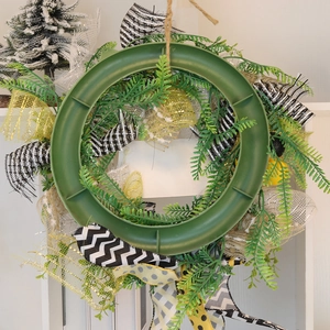 Bee festival welcome wreath base with green leaves, black and yellow ribbons on white backdrop