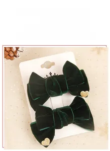 Detail of two dark green velvet hair clips with gold glitter hearts and white crown cards