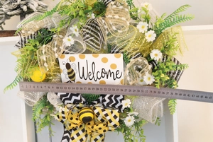 Detail showing bee-themed Welcome wreath with daisies and a scale measuring 40cm width
