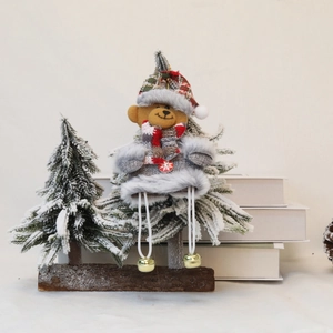 Detail of Christmas bear plush with gold bells and scarf on a snowy pine branch