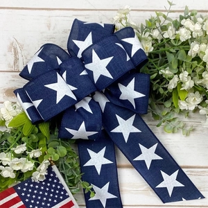 Blue burlap Independence Day bow with white stars and flag on a white wood background