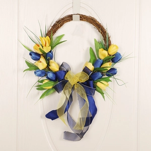 Blue and yellow faux tulip wreath on a brown rattan base with ribbon on a white door
